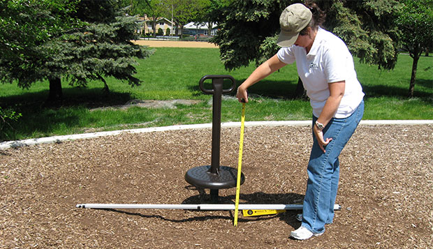 Photo of Consultant evaluating surface conditions of playspace (Source: US Access Board)